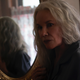 Barbara Hershey, with long grey hair, stands reflected in a mirror in horror movie The Manor.